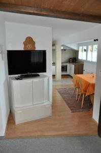 a living room with a flat screen tv on a white cabinet at Unterkunft in Zernez