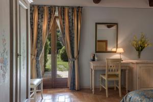 a bedroom with a bed and a desk and a window at Antica Fonte Resort in Casole dʼElsa