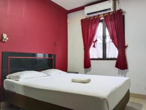 Un dormitorio con una cama con paredes rojas y una ventana en Metro Hotel Bekasi powered by Cocotel, en Pekayon Satu