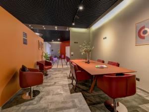 una sala de conferencias con mesa de madera y sillas rojas en B&B Hotel Quarto d'Altino, en Quarto dʼAltino