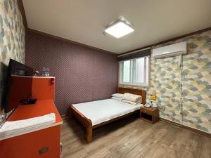 Cette petite chambre comprend un lit et une douche. dans l'établissement Swiss Motel, à Mokpo