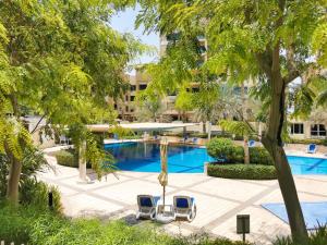 a swimming pool with two chairs and a hotel at Beautifully furnished 3BDR in Al Sidir Greens in Dubai