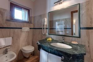 a bathroom with a sink and a toilet and a mirror at Antica Fonte Resort in Casole dʼElsa