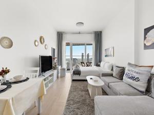 ein weißes Wohnzimmer mit einem Sofa und einem TV in der Unterkunft Spacious Studio With A Sofa Bed In JVC in Dubai