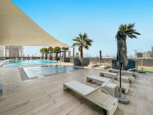einen Pool mit Liegestühlen und einem Sonnenschirm in der Unterkunft Spacious Studio With A Sofa Bed In JVC in Dubai