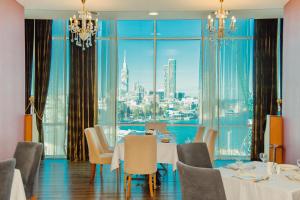 a dining room with a view of the city at JRW Welmond Hotel in Batumi