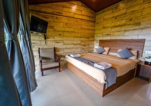 1 dormitorio con 1 cama, 1 silla y TV en Silent Valley Resort Ooty by VOYE HOMES, en Ooty
