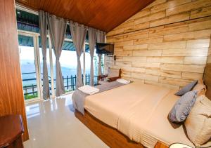 1 dormitorio con 1 cama con pared de madera en Silent Valley Resort Ooty by VOYE HOMES, en Ooty
