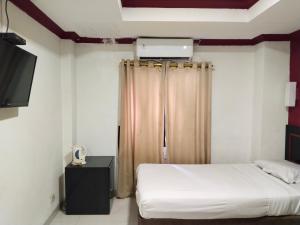 Habitación de hotel con cama y TV en Metro Hotel Bekasi powered by Cocotel, en Pekayon Satu