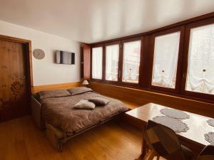 Un dormitorio con una cama y una mesa y ventanas. en Charlotte Lodge 28, en Breuil-Cervinia