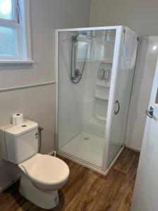 La salle de bains est pourvue de toilettes et d'une douche en verre. dans l'établissement Oasis Motel - waiouru, à Waiouru