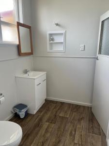 La salle de bains est pourvue de toilettes, d'un lavabo et d'un miroir. dans l'établissement Oasis Motel - waiouru, à Waiouru
