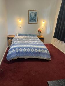 懷烏魯的住宿－Oasis Motel - waiouru，一间卧室配有一张带蓝色棉被的床