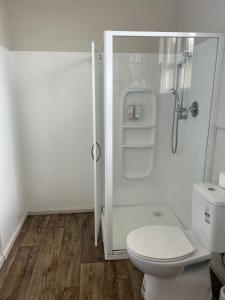 La salle de bains blanche est pourvue d'une douche et de toilettes. dans l'établissement Oasis Motel - waiouru, à Waiouru