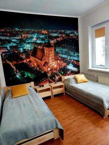 ein Schlafzimmer mit einem Wandbild einer Stadt in der Nacht in der Unterkunft Szkolne Schronisko Mlodziezowe w Olsztynie in Olsztyn