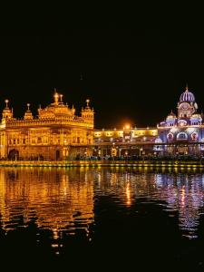 un grand bâtiment avec des lumières sur l'eau la nuit dans l'établissement The heaven(close to golden temple), à Amritsar