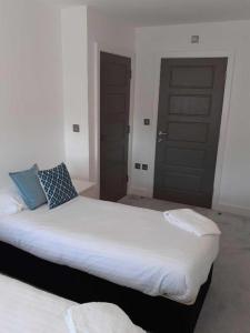 a bedroom with a large white bed with a black door at IR Icon Brentwood Town in Brentwood