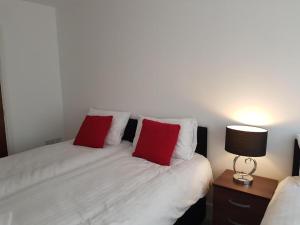 een slaapkamer met een bed met 2 rode kussens bij IR Icon Brentwood Town in Brentwood