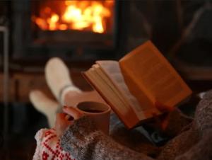 una persona está sosteniendo un libro y una taza de café en NEU Luxuriöses Tinyhaus Ferienhaus FREYR einmalig in Lübbenau, en Klein Klessow