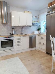 a kitchen with white cabinets and stainless steel appliances at Persoonallinen pieni asunto in Oulu