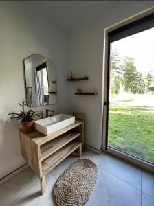 La salle de bains est pourvue d'un lavabo, d'un miroir et d'une fenêtre. dans l'établissement Peaceful holiday house Pāvilosta, à Pāvilosta