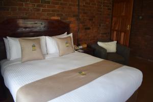 een groot bed met kussens en een stoel in een kamer bij 1 bedroomed chalet in Harare - 2183 in Kingsmead