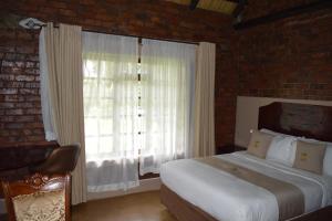 een slaapkamer met een bed en een groot raam bij 1 bedroomed chalet in Harare - 2183 in Kingsmead