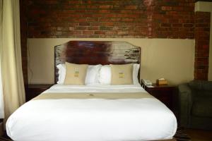 een slaapkamer met een wit bed en een bakstenen muur bij 1 bedroomed chalet in Harare - 2183 in Kingsmead