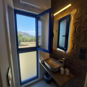 baño con lavabo y 2 ventanas en NAVARINO BATHS sea-front estate en Vromonérion