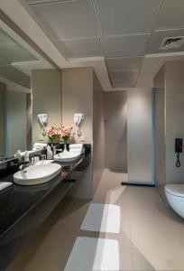 a bathroom with three sinks and a toilet at HDB Financial District in Riyadh