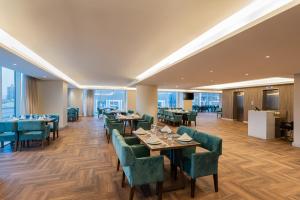 a dining room with tables and green chairs at HDB Financial District in Riyadh