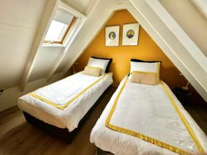 twee bedden in een kamer met een zolder bij Polderhuus Galatheapolder in Achthuizen
