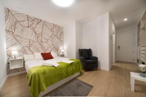 een slaapkamer met een bed met een groene deken en een stoel bij Vizcainos Garden in Segovia