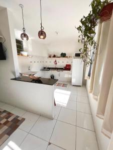 cocina blanca con encimera negra y electrodomésticos blancos en Kitnet na Vila de Manguinhos en Serra