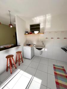 una pequeña cocina con fregadero y 2 taburetes en Kitnet na Vila de Manguinhos en Serra
