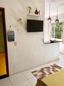 a living room with a flat screen tv on a wall at Kitnet na Vila de Manguinhos in Serra