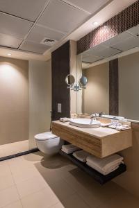 W łazience znajduje się umywalka, toaleta i lustro. w obiekcie HDB Financial District w Rijadzie