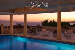 a swimming pool with chairs and a sunset at Martin 's Villa. House on the beach with pool in Lloret de Mar