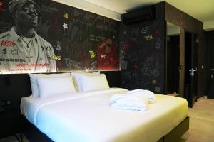 a bedroom with a bed with white sheets and a wall with graffiti at SO City Hotel Adults Only in St. Julianʼs