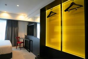 a room with a bed and a desk and a yellow wall at SO City Hotel Adults Only in St. Julianʼs