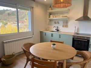 uma cozinha com uma mesa de madeira com cadeiras e um lavatório em Casa Catalina - Ribeira Sacra em Abeleda