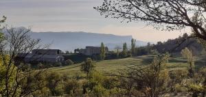 een veld met een huis en een berg op de achtergrond bij Charmante chambre d'hôtes en pleine nature in Orpierre