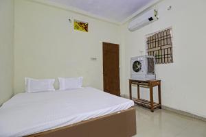 a bedroom with a white bed and a microwave at SPOT ON 81062 Moonlight Hotel in Bhilai