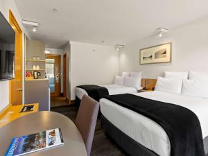 a hotel room with two beds and a table at Novotel Queenstown Lakeside in Queenstown