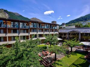 um hotel com um pátio com mesas e árvores em Novotel Queenstown Lakeside em Queenstown