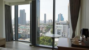 um quarto com grandes janelas com vista para a cidade em Shenzhen Tower Hotel Thonglor Sukhumvit em Banguecoque