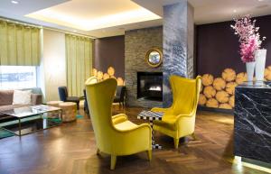 een woonkamer met gele stoelen en een open haard bij South Place Hotel in Londen