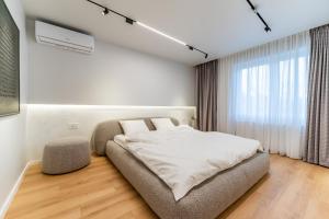 a white bedroom with a bed and a window at Kuib Central Apartament in Arad