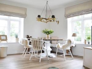 ein Esszimmer mit weißen Stühlen und einem Tisch in der Unterkunft Holiday apartment Domstag "Kos" in Kronsgaard