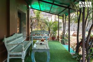 a porch with a bench and a table with tea on it at StayVista's Apple Farms - Urban Oasis with Outdoor Pool & Expansive Lawn in Sohna